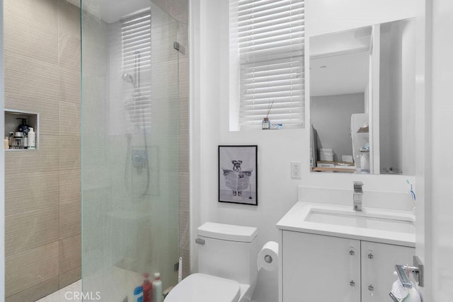 bathroom with a shower with door, vanity, and toilet