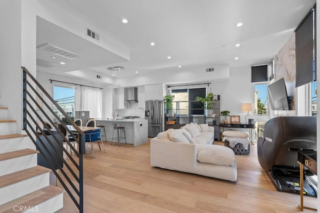 living room with sink, a wealth of natural light, and light hardwood / wood-style floors