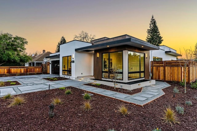 back house at dusk featuring a garage