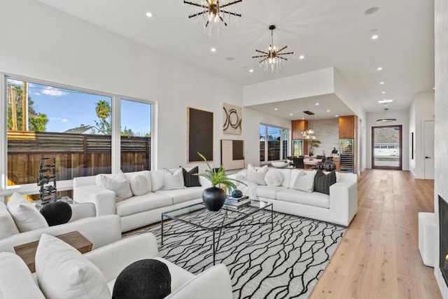 living room featuring an inviting chandelier, light hardwood / wood-style flooring, and a wealth of natural light