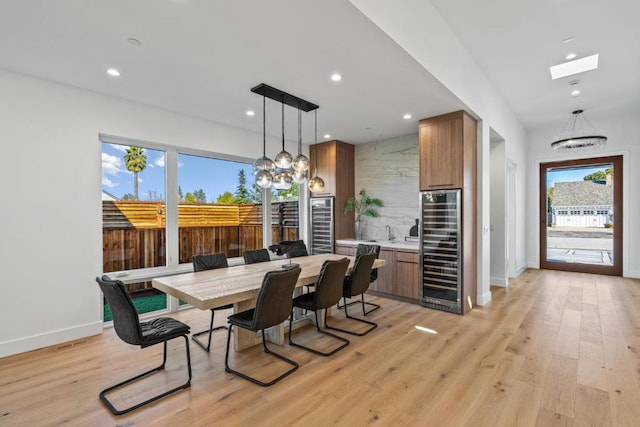 dining space featuring wine cooler, a notable chandelier, and light wood-type flooring