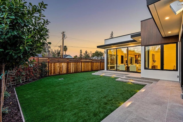 yard at dusk featuring a patio