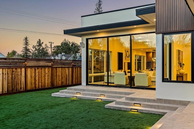 exterior entry at dusk featuring a yard and a patio area