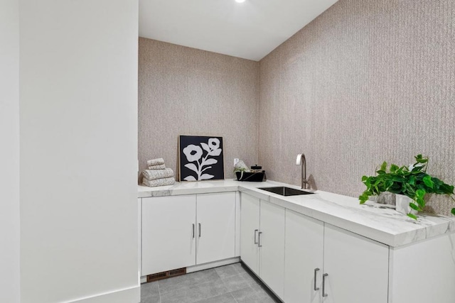 kitchen featuring white cabinetry, light tile patterned flooring, kitchen peninsula, and sink