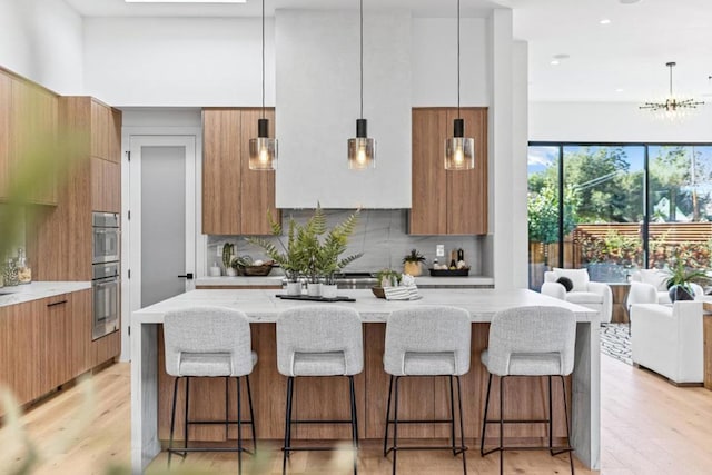 kitchen featuring pendant lighting, backsplash, and light stone counters