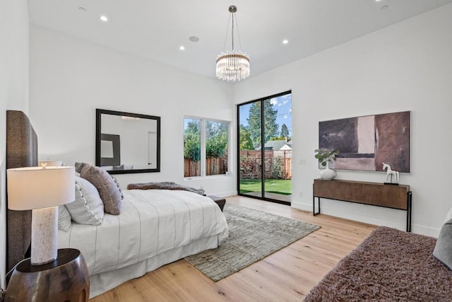 bedroom with a notable chandelier, light hardwood / wood-style flooring, and access to outside