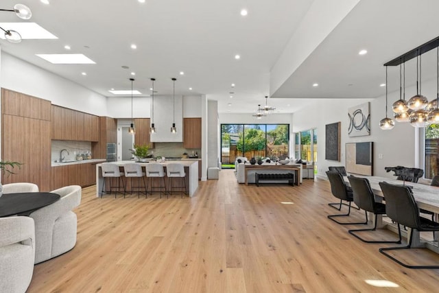 living room with a towering ceiling, sink, light hardwood / wood-style flooring, and a notable chandelier