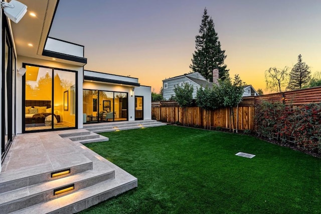 yard at dusk featuring a patio