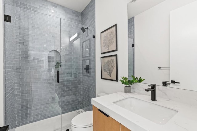 bathroom featuring vanity, toilet, and a shower with door