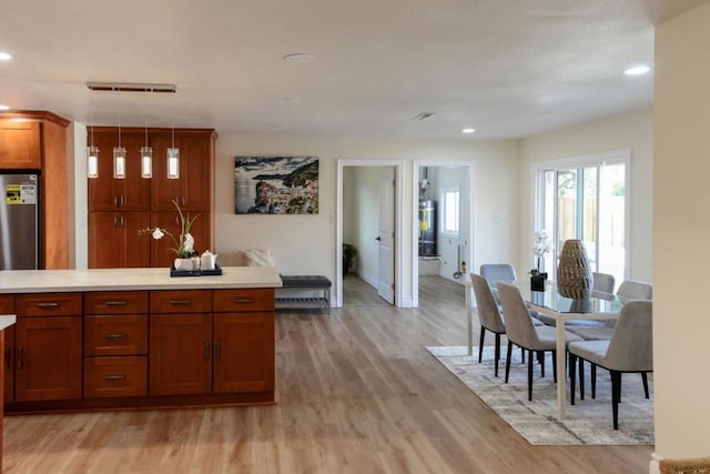 kitchen featuring fridge, decorative light fixtures, and light wood-type flooring