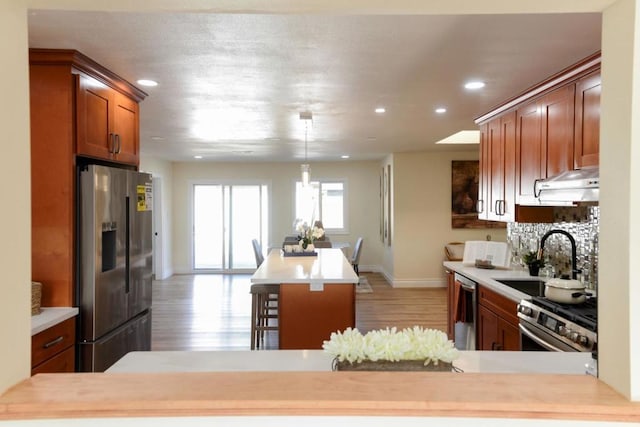 kitchen featuring appliances with stainless steel finishes, sink, backsplash, a kitchen breakfast bar, and light hardwood / wood-style floors