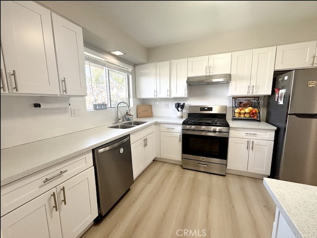 kitchen featuring white cabinets, under cabinet range hood, stainless steel appliances, and a sink