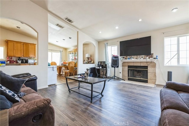 living room with lofted ceiling, hardwood / wood-style flooring, and a tile fireplace