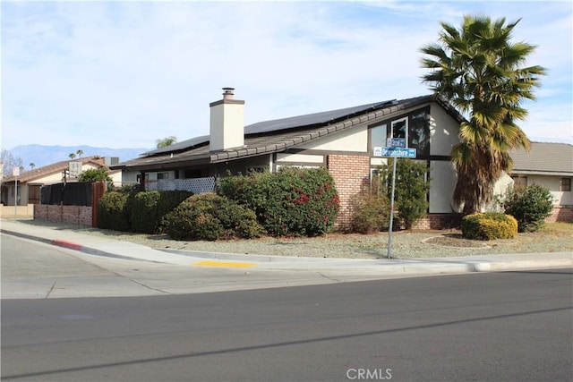 view of side of home with a mountain view and solar panels