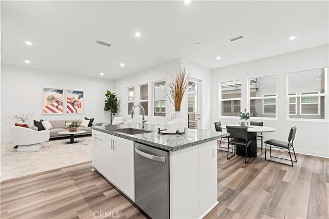 kitchen with sink, stainless steel dishwasher, white cabinets, and a center island with sink