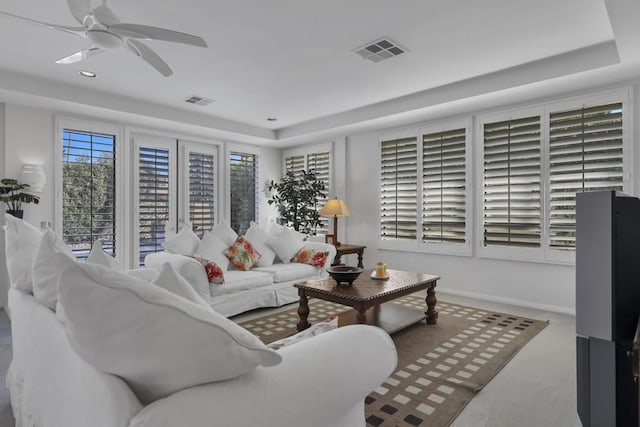 carpeted living room with a tray ceiling and ceiling fan