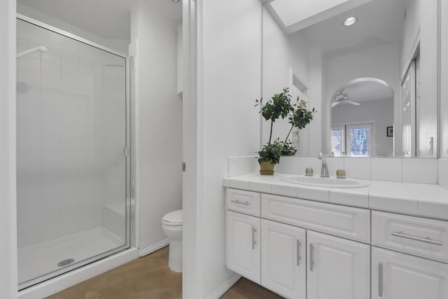 bathroom with ceiling fan, hardwood / wood-style floors, vanity, a shower with shower door, and toilet