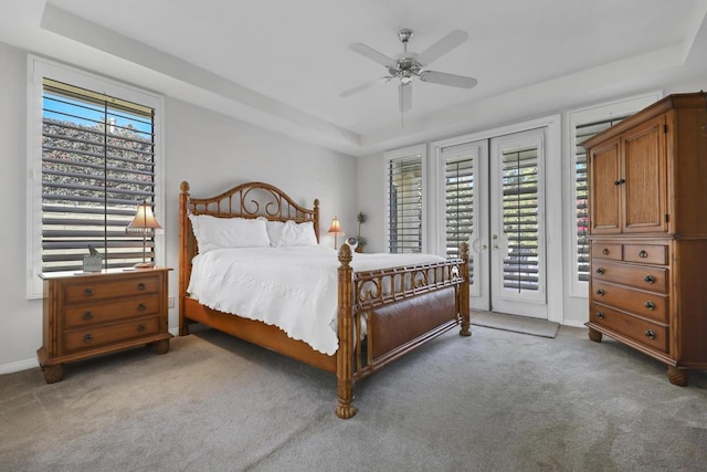 carpeted bedroom with multiple windows, access to outside, a raised ceiling, and french doors