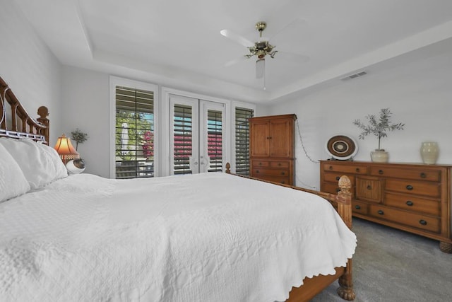 bedroom featuring french doors, ceiling fan, dark carpet, and a tray ceiling