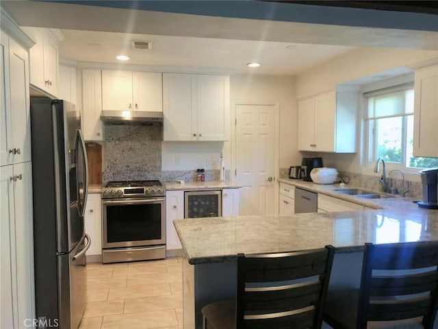 kitchen featuring stainless steel appliances, white cabinetry, and kitchen peninsula