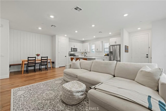 living area featuring light wood-style flooring, visible vents, and recessed lighting