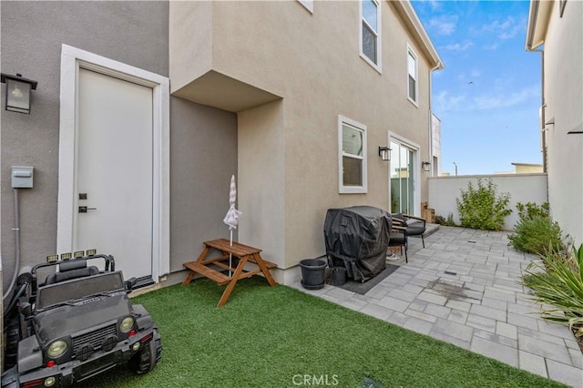 rear view of property featuring a yard, a patio area, fence, and stucco siding