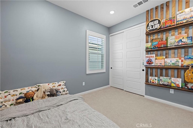 bedroom with baseboards, visible vents, a closet, and light colored carpet