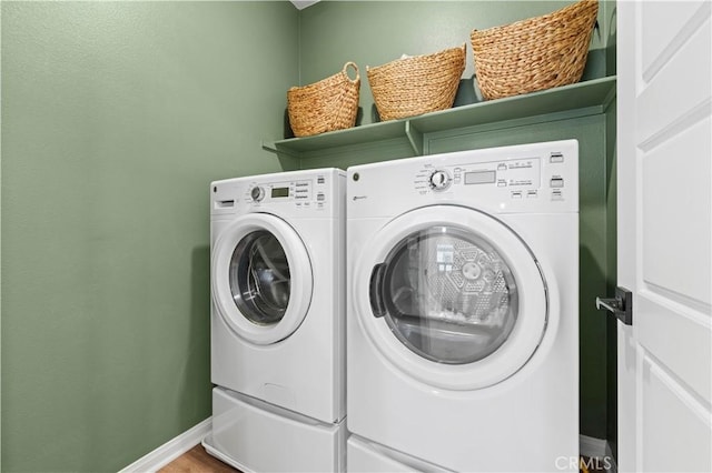 laundry area with laundry area, washing machine and dryer, and baseboards