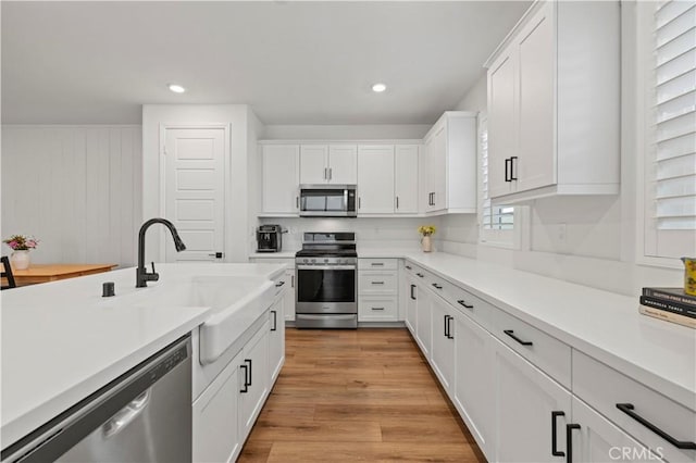 kitchen with light countertops, appliances with stainless steel finishes, a sink, and white cabinetry