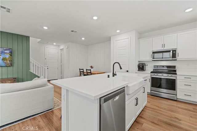 kitchen featuring stainless steel appliances, light countertops, a center island with sink, and white cabinets