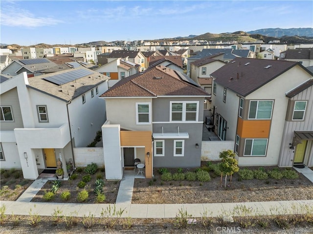 view of front facade with a residential view, roof with shingles, a mountain view, and stucco siding