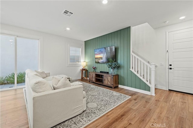 living area featuring stairs, light wood-style flooring, visible vents, and a healthy amount of sunlight