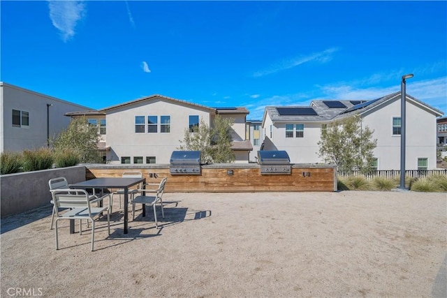 view of patio / terrace with grilling area, a residential view, fence, and an outdoor kitchen