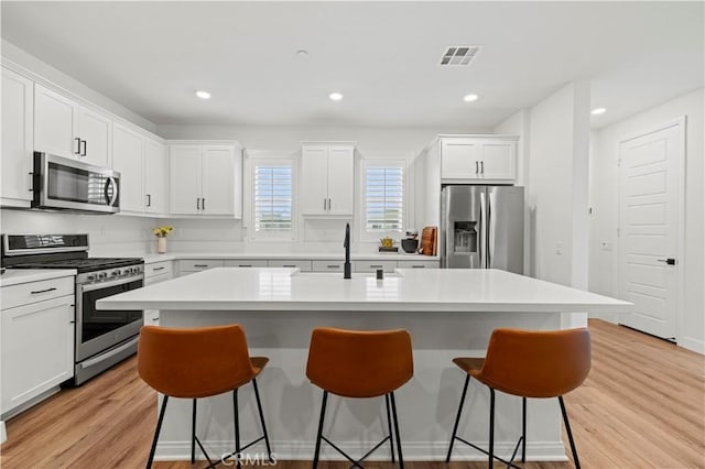 kitchen with appliances with stainless steel finishes, light countertops, and a center island with sink