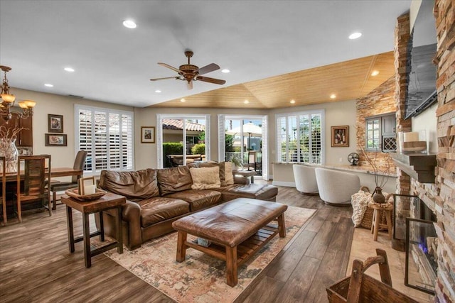 living room featuring ceiling fan with notable chandelier, lofted ceiling, hardwood / wood-style floors, and a fireplace