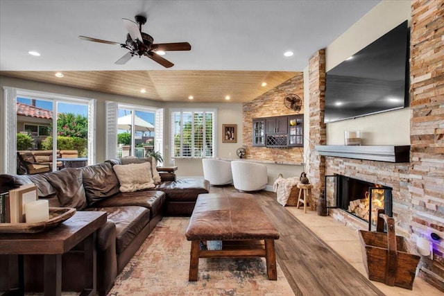 living room with ceiling fan, a fireplace, vaulted ceiling, wooden ceiling, and light wood-type flooring