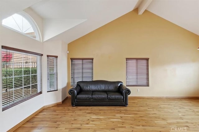 living area featuring beam ceiling, high vaulted ceiling, and light wood-type flooring