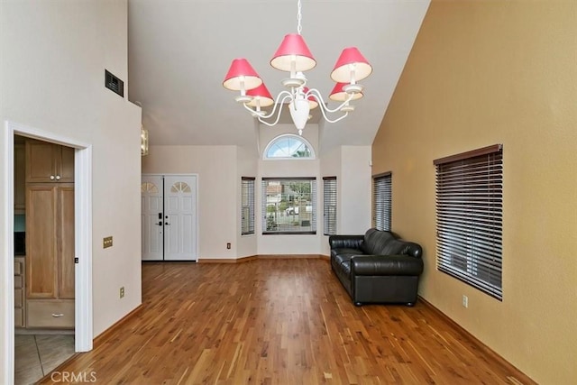 interior space featuring an inviting chandelier, hardwood / wood-style flooring, and high vaulted ceiling