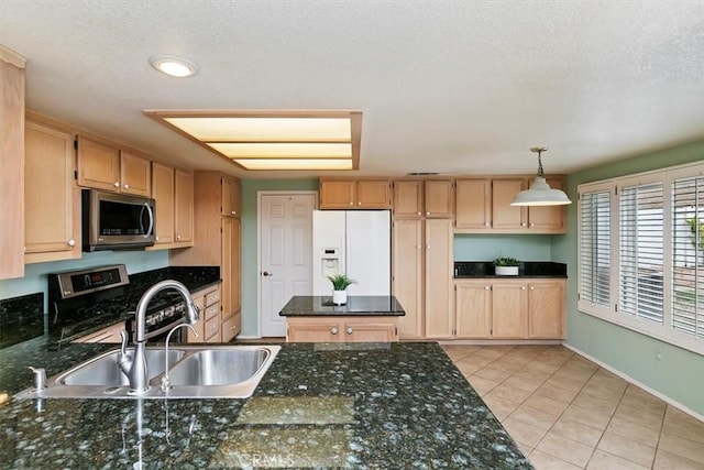 kitchen featuring light brown cabinetry, hanging light fixtures, light tile patterned floors, and stainless steel appliances