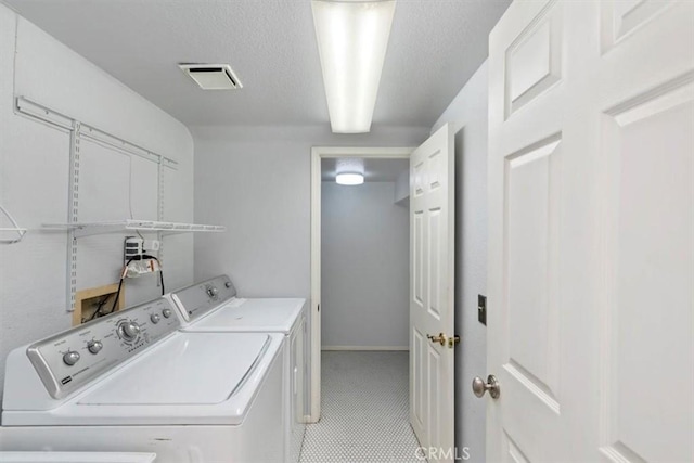 clothes washing area with separate washer and dryer and a textured ceiling