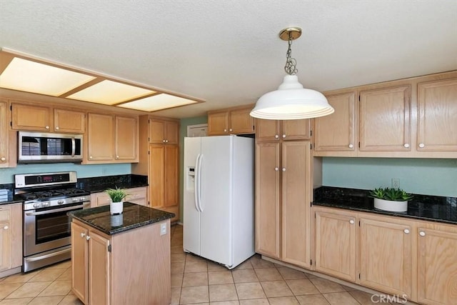 kitchen with appliances with stainless steel finishes, pendant lighting, dark stone countertops, a center island, and light tile patterned floors