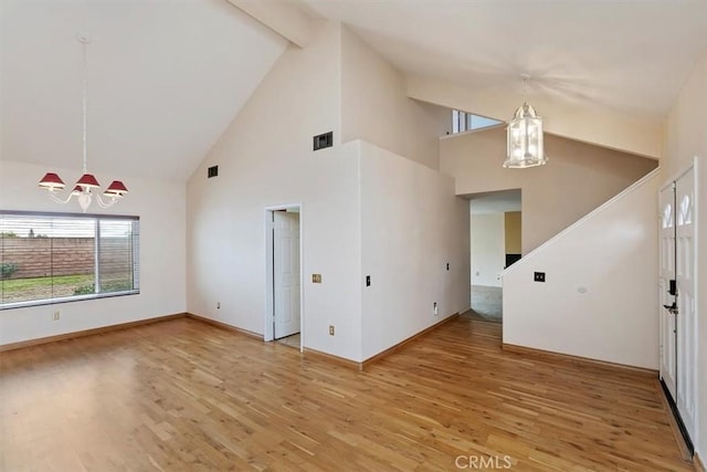 unfurnished living room featuring an inviting chandelier, hardwood / wood-style floors, high vaulted ceiling, and beamed ceiling