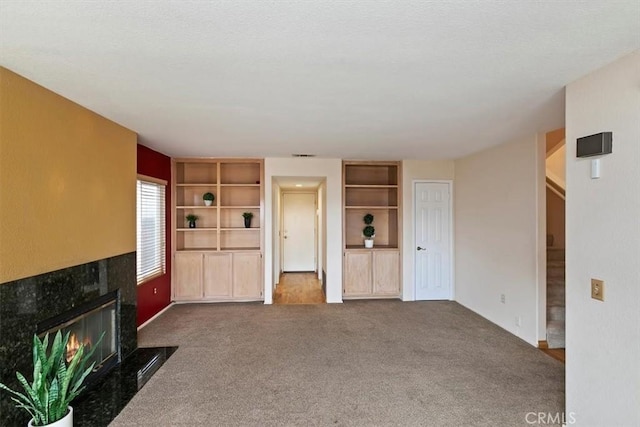 unfurnished living room featuring carpet flooring and a high end fireplace