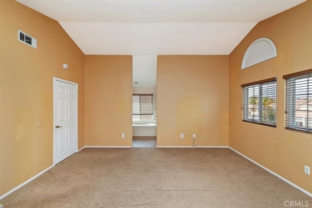 carpeted empty room featuring high vaulted ceiling