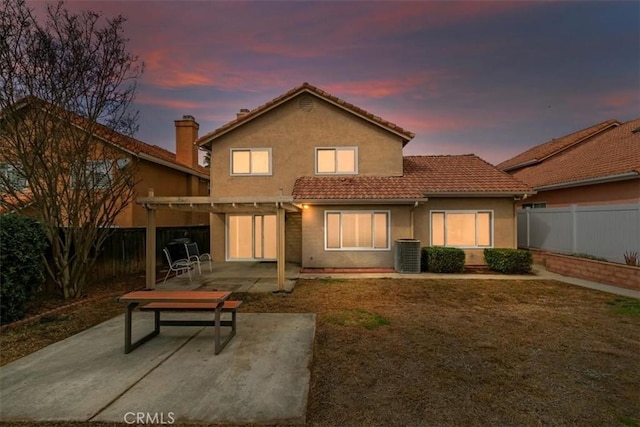 back house at dusk featuring a yard, a pergola, a patio area, and central air condition unit