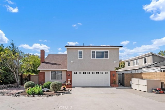 traditional-style home featuring concrete driveway, a chimney, an attached garage, fence, and stucco siding