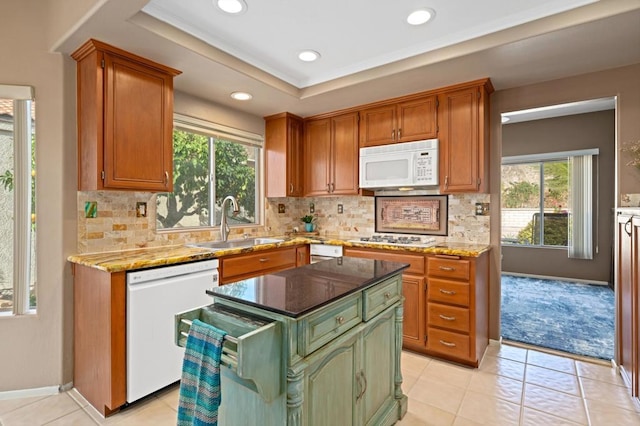 kitchen with sink, white appliances, dark stone counters, and a kitchen island