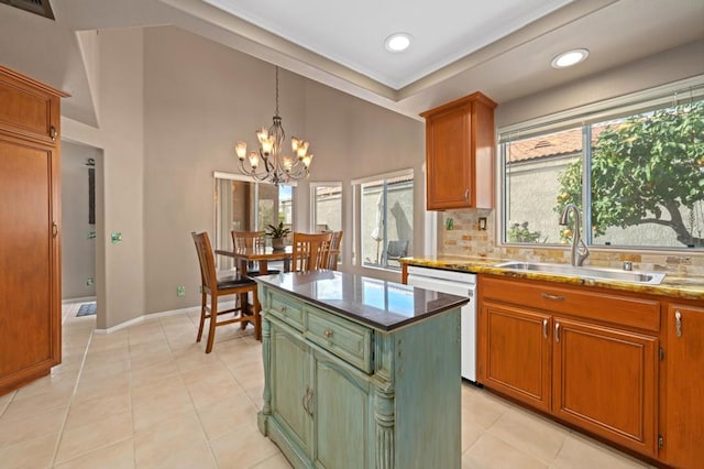 kitchen with sink, hanging light fixtures, dishwasher, a kitchen island, and decorative backsplash