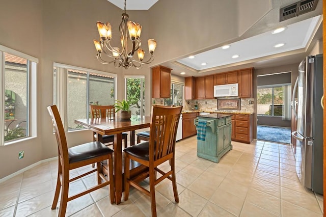 tiled dining space with an inviting chandelier, a tray ceiling, and sink