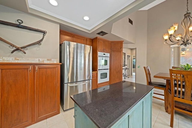 kitchen featuring double oven, stainless steel fridge, a center island, and a raised ceiling